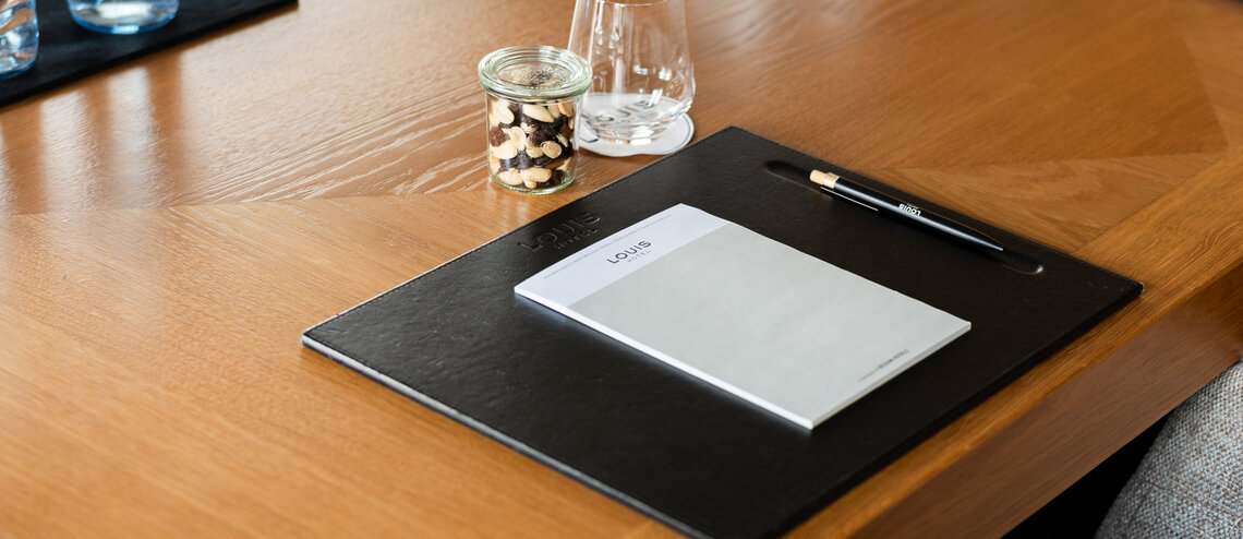 : © Tony Gigov A notepad and glasses of water on a wooden table.