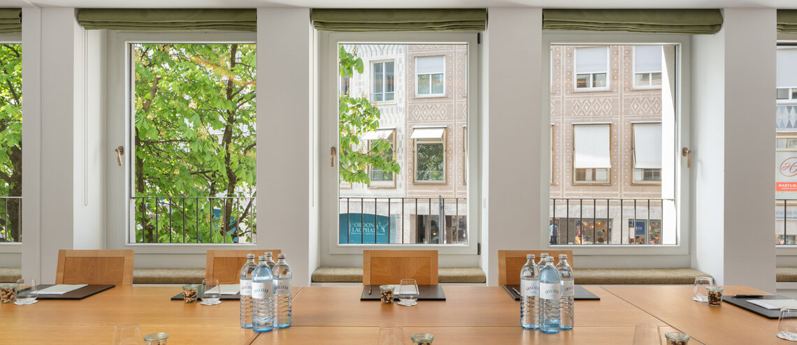 Ausblick aus dem Tagungsraum auf umliegende Häuser und grüne Bäume.