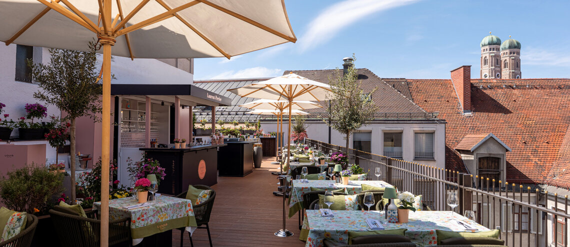 : © Tony Gigov The roof terrace with parasols, plenty of colourful seating areas and a view of the Frauenkirche.