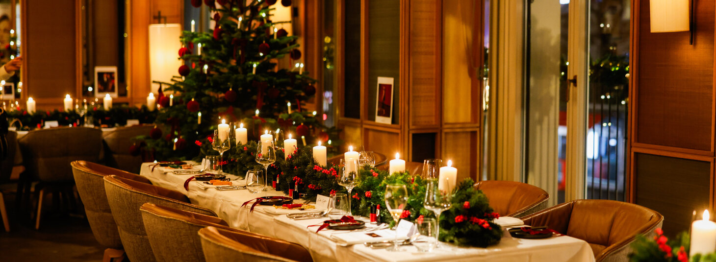 A festively decorated table stands in the Grillroom restaurant, with a Christmas tree in the background.
