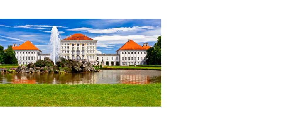 Barockes Schloss mit rotem Dach, großem Brunnen im Vordergrund und gepflegtem Rasen, unter blauem Himmel.
