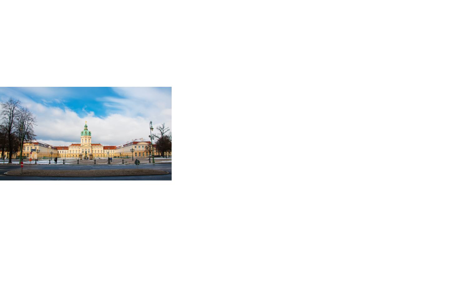 Schloss mit rotem Dach und Turm, umgeben von Bäumen, unter blauem Himmel mit Wolken.