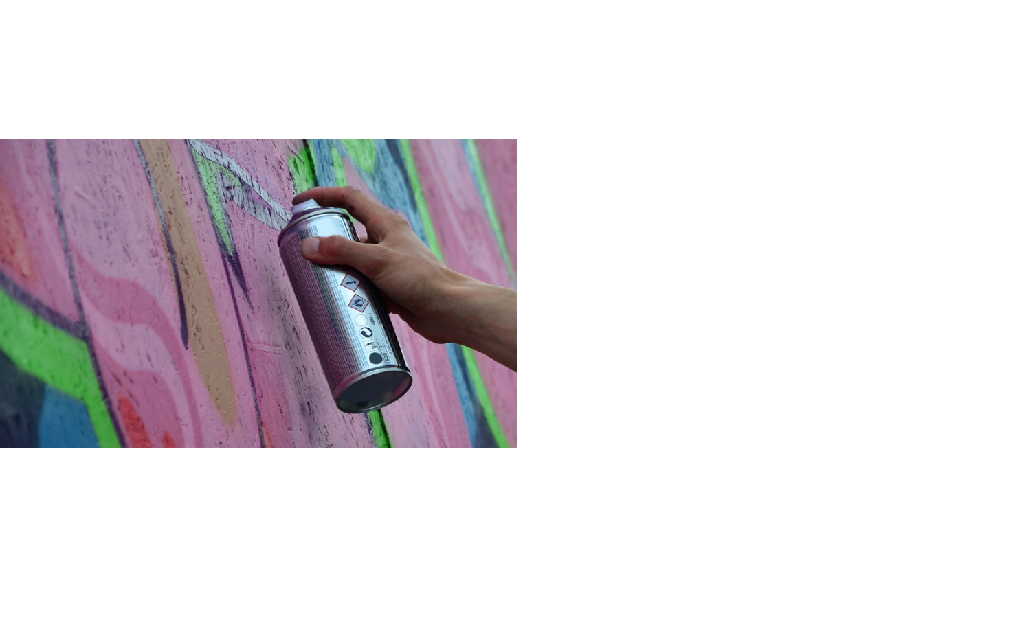 Eine Hand sprüht bunte Graffiti auf eine Wand mit einer Spraydose.