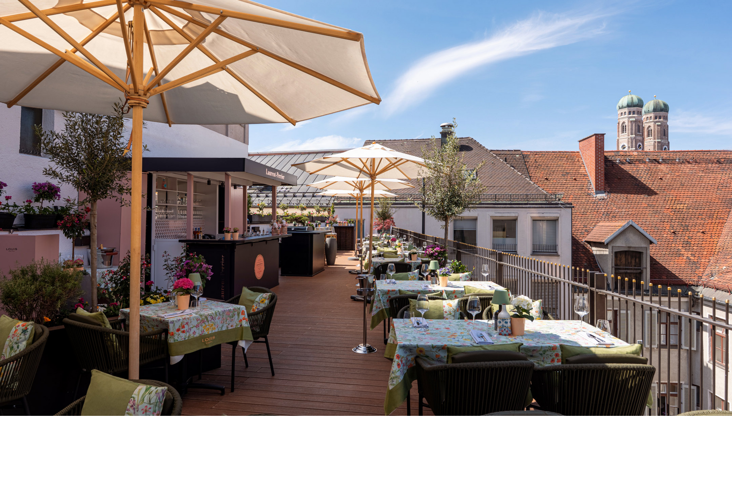 Die Dachterrasse mit Sonnenschirmen, vielen bunten Sitzgruppen und Blick auf die Frauenkirche.