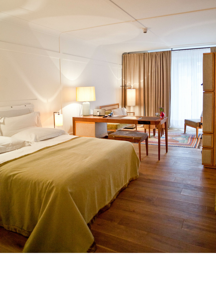 Gemütliches Hotelzimmer mit Doppelbett, Schreibtisch, Sesseln und großen Fenstern mit Vorhängen im LOUIS Hotel München.