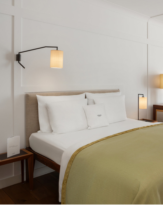 Gemütliches Hotelzimmer mit Doppelbett, Schreibtisch, Sesseln und großen Fenstern mit Vorhängen im LOUIS Hotel München.
