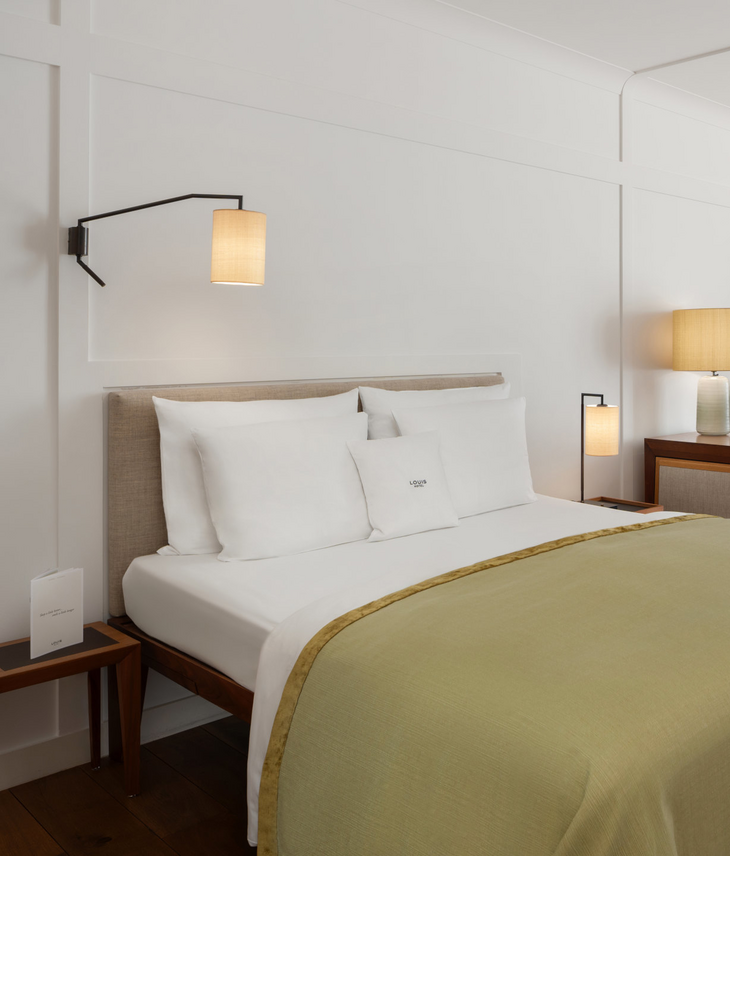 Gemütliches Hotelzimmer mit Doppelbett, Schreibtisch, Sesseln und großen Fenstern mit Vorhängen im LOUIS Hotel München.