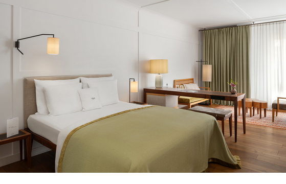 Gemütliches Hotelzimmer mit Doppelbett, Schreibtisch, Sesseln und großen Fenstern mit Vorhängen im LOUIS Hotel München.