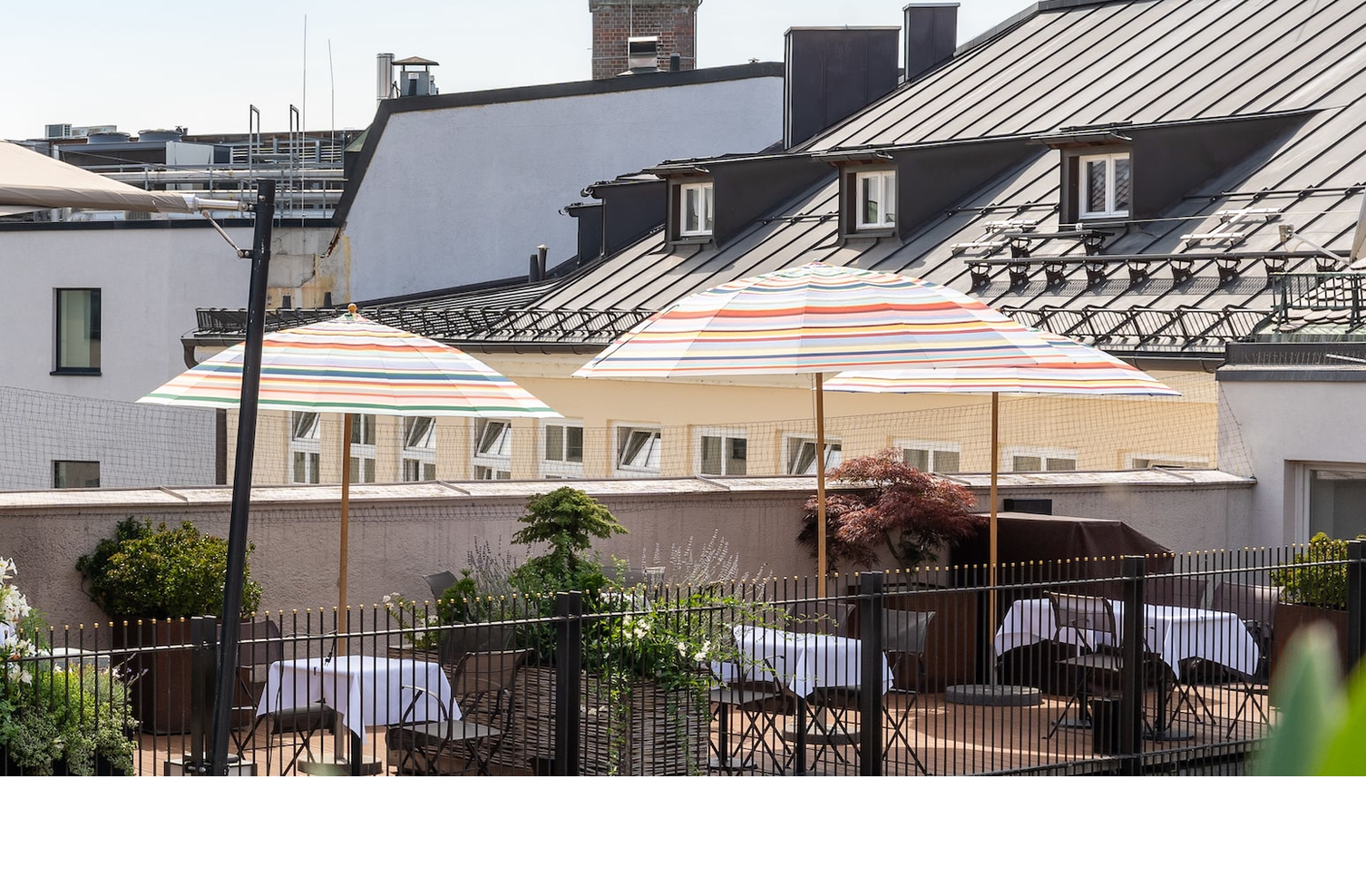 Tische und Sonnenschirme auf der The LOUIS Roof Terrace, Restaurant und Rooftopbar in München