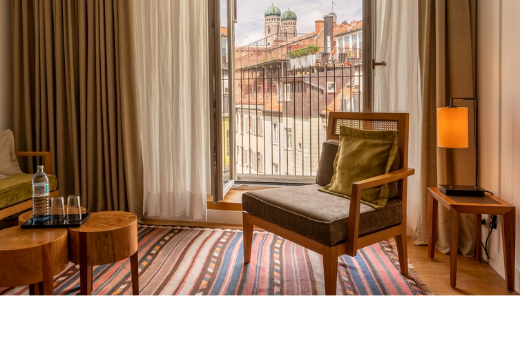 Wohnbereich mit Sessel im Hotelzimmer Market View, Fenster mit Blick auf Viktualienmarkt in München