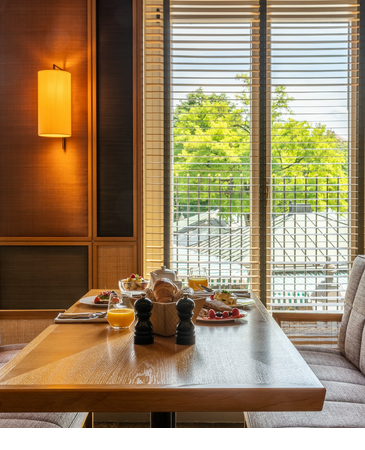 Tisch mit Fruehstueck und Fenster mit Blick auf Viktualienmarkt im LOUIS Hotel Muenchen