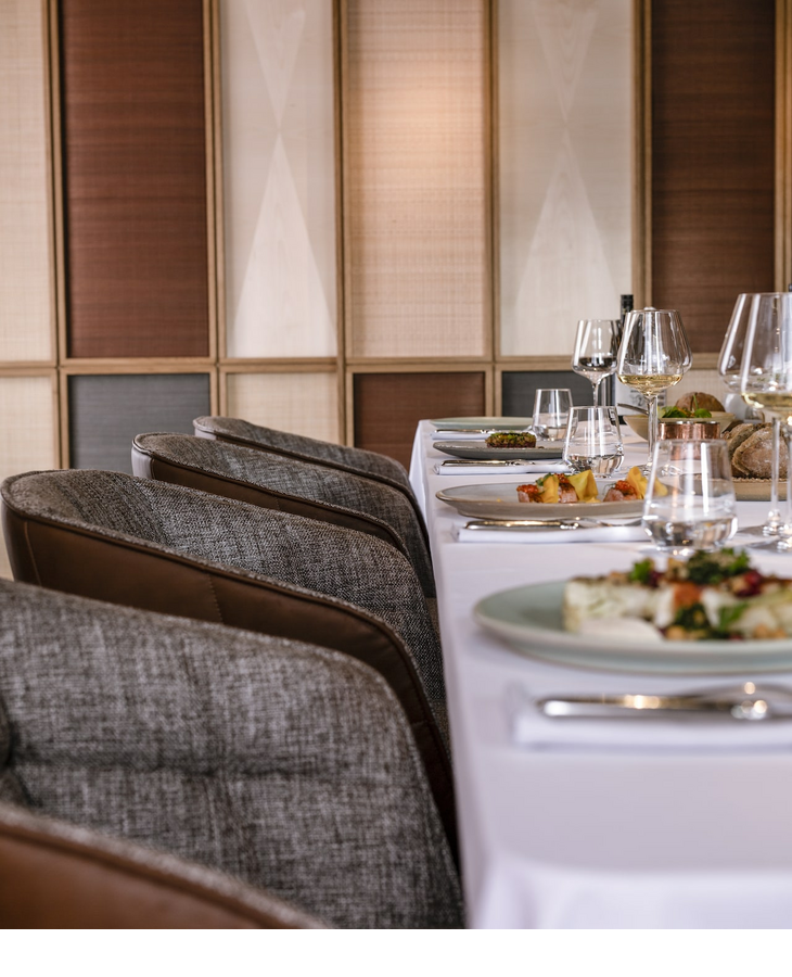Elegant restaurant in the LOUIS Hotel Munich with a laid table and modern, upholstered chairs.