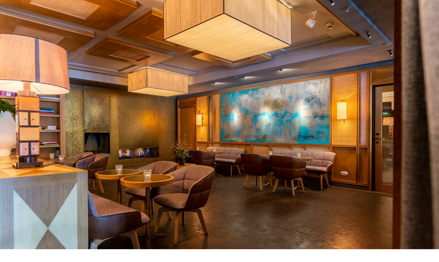 Cozy hotel lounge with modern furniture, fireplace and large abstract artwork on the wall.