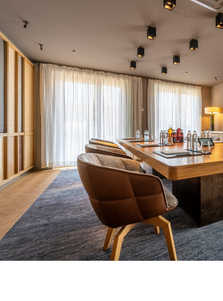 Moderner Konferenzraum im LOUIS Hotel München mit großem Holztisch, stilvollen Stühlen und natürlichem Licht.