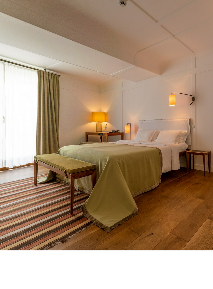 Superior room at the LOUIS Hotel Munich Bright hotel room with double bed, bedside tables, armchair, desk and lamp, wooden floor and curtains.