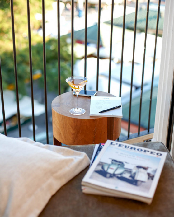 View from the balcony of the LOUIS Hotel: table with drink, notepad, pen and book, with a view of the green market.
