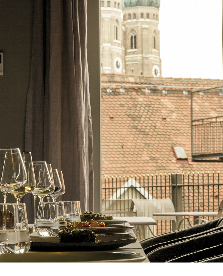 Gedeckter Tisch im Hotelzimmer mit Blick auf die Türme der Frauenkirche in München.