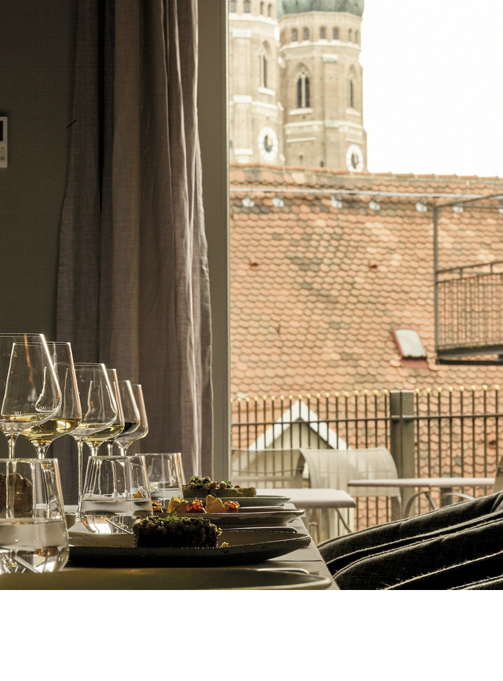 Gedeckter Tisch im Hotelzimmer mit Blick auf die Türme der Frauenkirche in München.