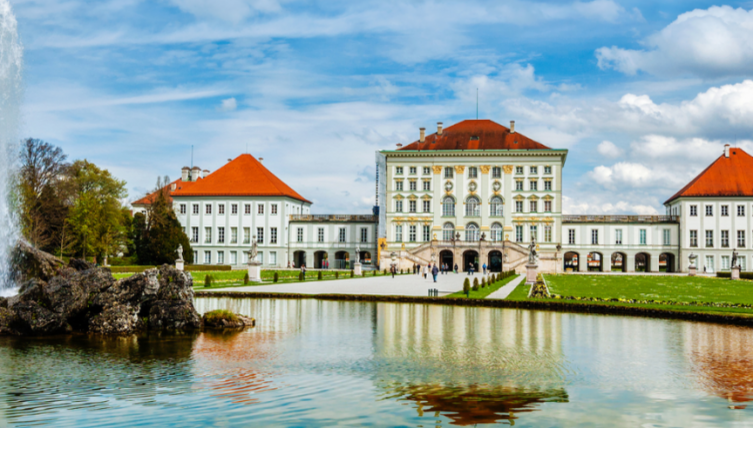 Schloss Nymphenburg in München, mit symmetrischem Barockbau, rotem Dach, Park und Teich im Vordergrund.