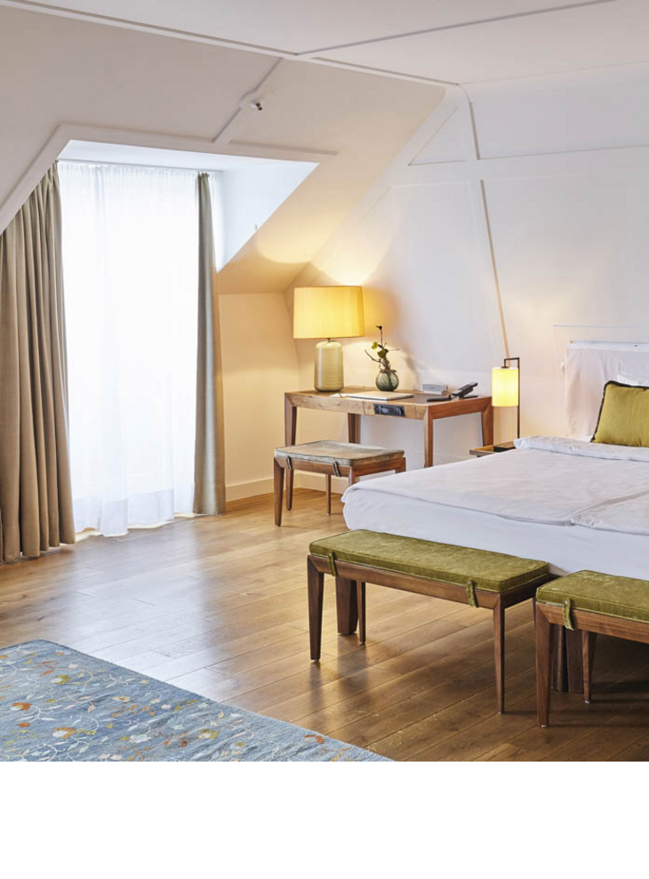 Large double bed and a desk in the suite at the LOUIS Hotel Munich