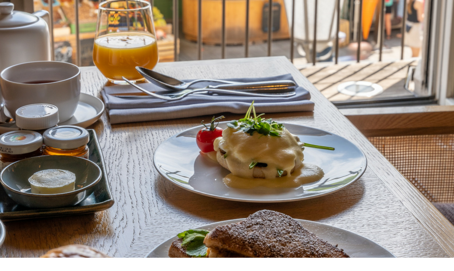 Frühstückstisch im LOUIS Hotel mit Gebäck, Eiern, Saft und Blick auf den belebten Viktualienmarkt in München.