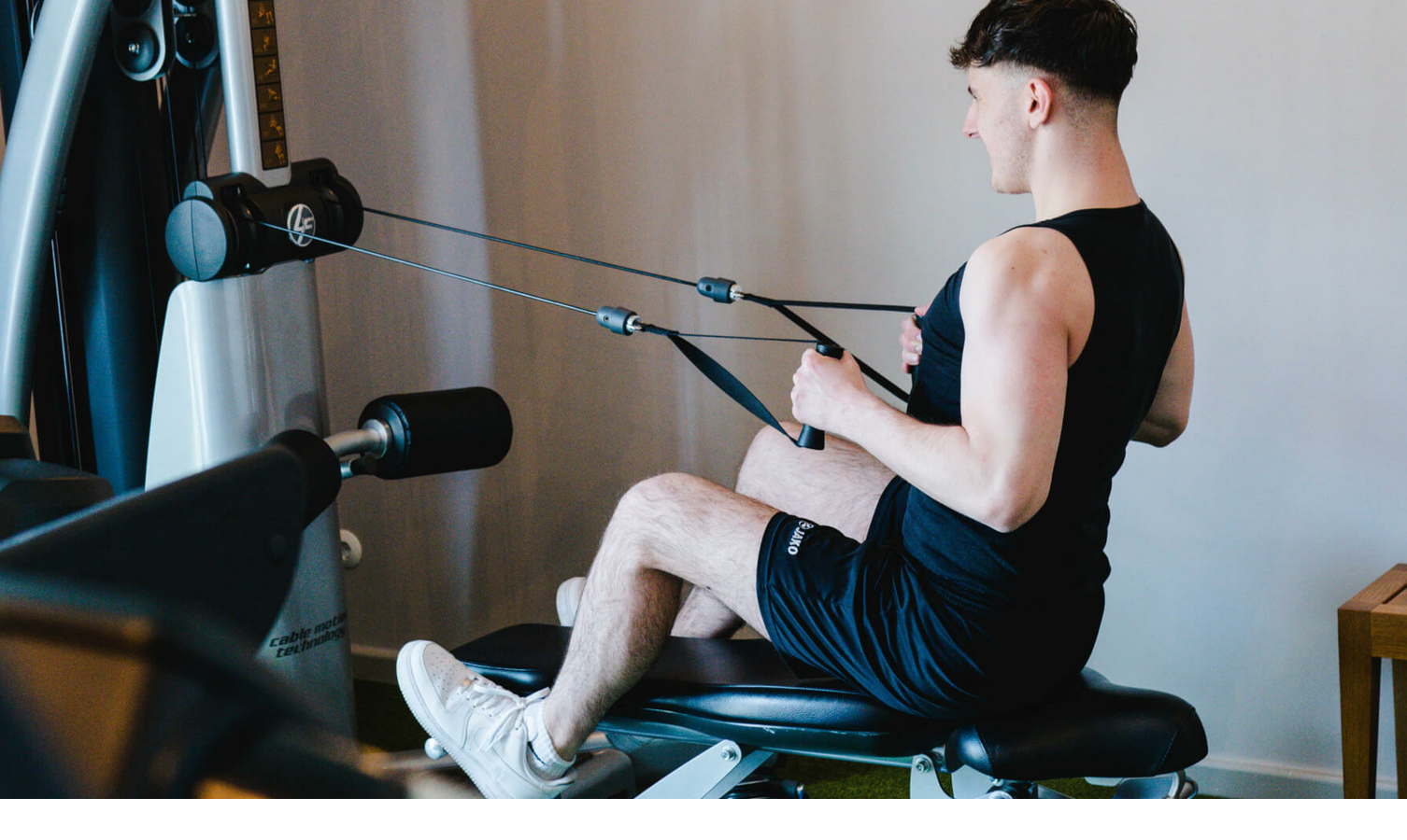 LOUIS Fitness Gym mit Crosstrainer, Fahrrad, Laufband und einer Krafttrainingsstation Person trainiert an Fitnessgerät im LOUIS Hotel München. Moderner Fitnessraum mit Krafttrainingsmöglichkeiten.
