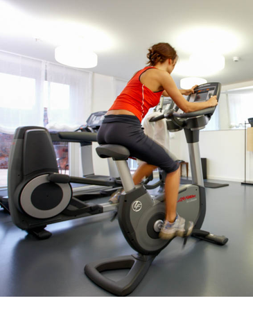Woman on bike in the fitness gym of the LOUIS Hotel Munich