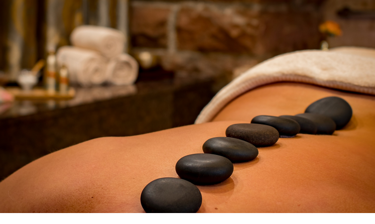 Person bei einer Hot-Stone-Massage im LOUIS Hotel München, mit dunklen Steinen auf dem Rücken.