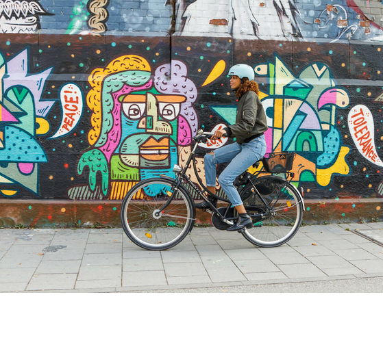 Person auf Fahrrad vor bunter Graffiti-Wand mit den Worten "Peace" und "Tolerance".