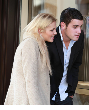 A couple looks at a Cartier window display with watches and a red box.