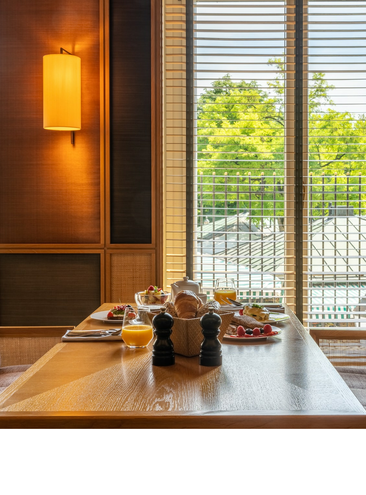 Tisch mit Fruehstueck und Fenster mit Blick auf Viktualienmarkt im LOUIS Hotel Muenchen