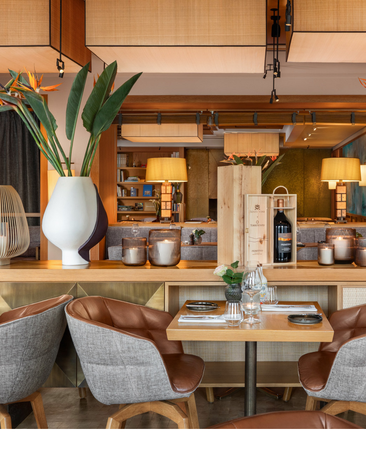 A cosy breakfast area at the LOUIS Hotel Munich, featuring a laid table and warm wooden accents complemented by green plants.