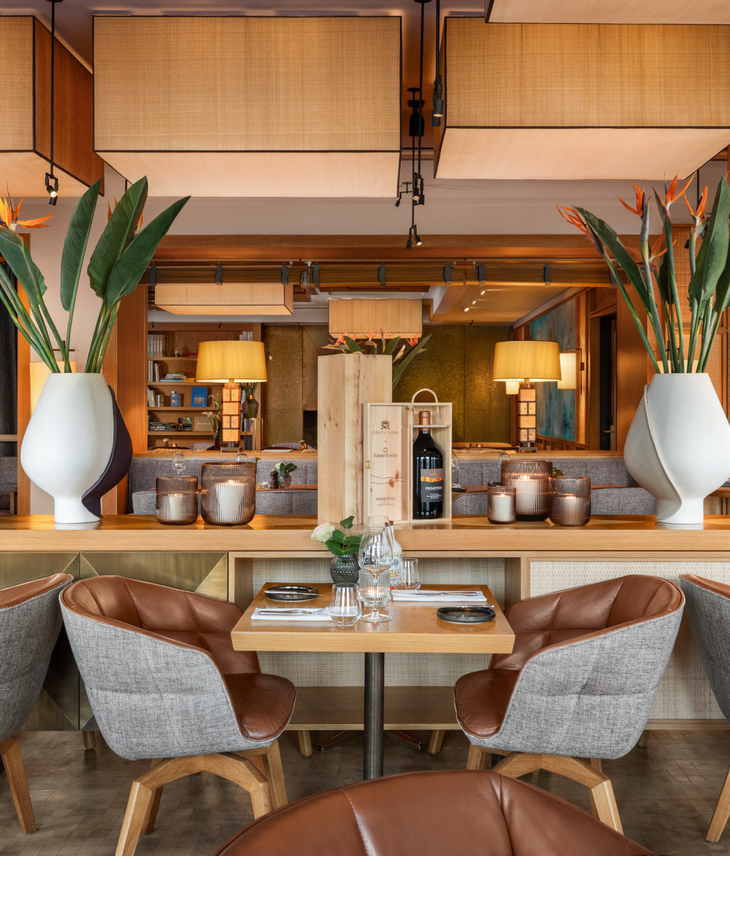 Gemütlicher Frühstücksbereich im LOUIS Hotel München mit gedecktem Tisch und warmen Holzakzenten mit grünen Pflanzen.