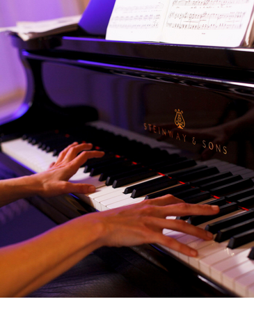 Hände spielen Klavier, Notenblätter auf dem Piano, elegante Atmosphäre.