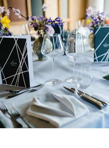 Elegant table decorations at the LOUIS Hotel Munich with flowers, glasses and stylish menu cards.