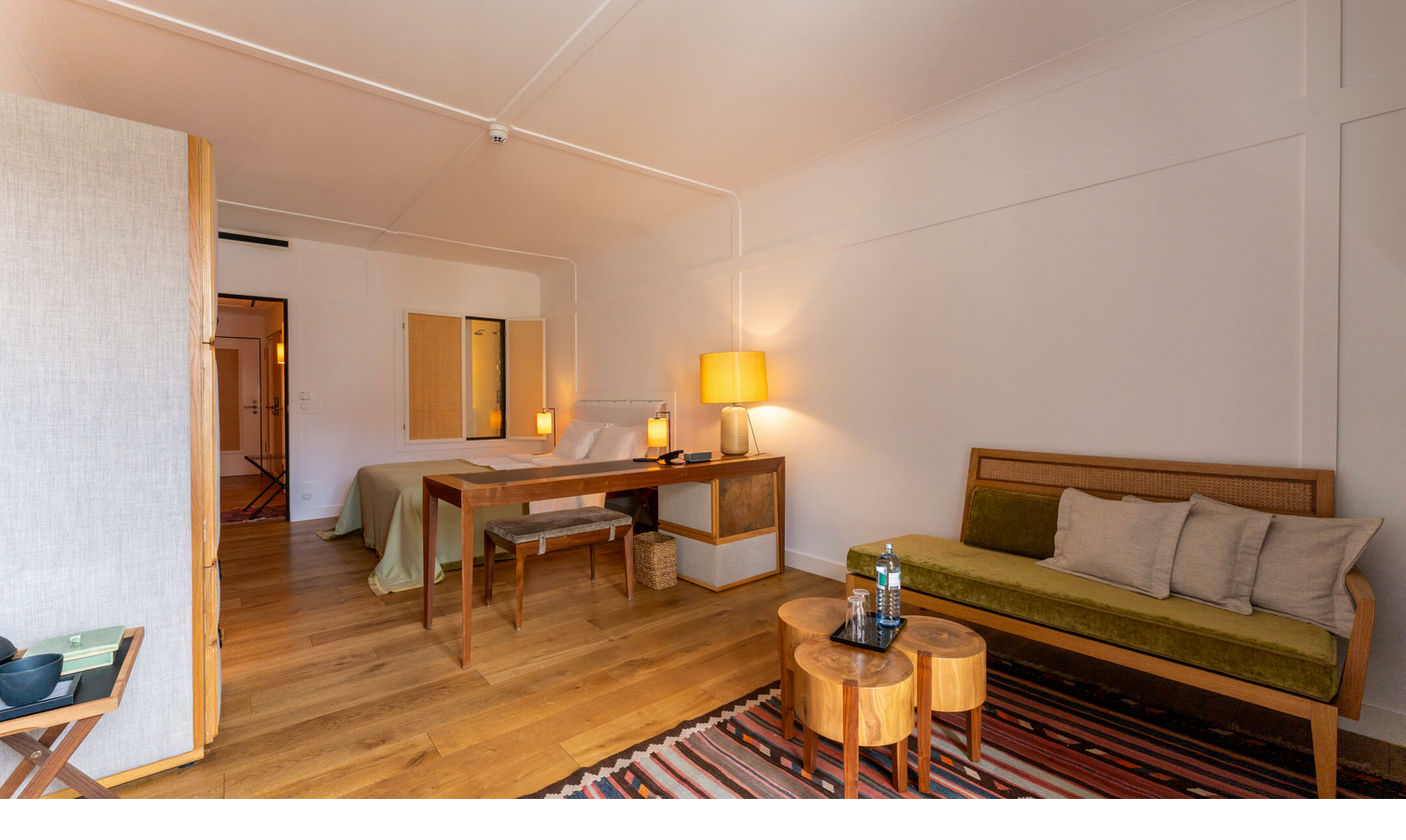 LOUIS Hotel München | Zimmer Market View Deluxe Helles Hotelzimmer mit Holzboden, Bett, Schreibtisch, Sofa, Teppich und Tischlampen im LOUIS Hotel München.