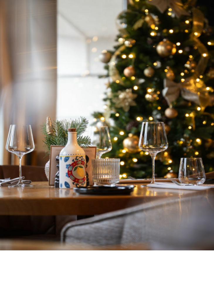 Gläser die auf einem Tisch stehen. Im Hintergrund ist ein geschmückter Weihnachtsbaum zu sehen.