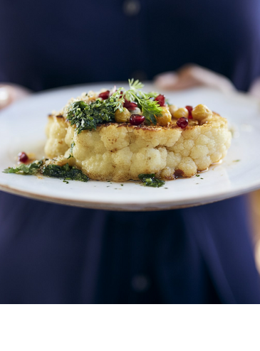 Grillroom Restaurant LOUIS Hotel Muenchen Ein Teller mit kunstvoll angerichtetem Blumenkohl, garniert mit Kräutern und Granatapfelkernen.