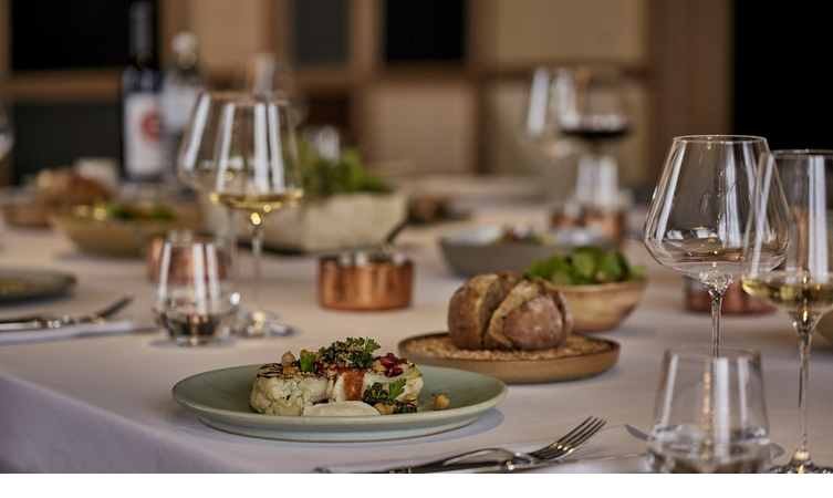 Eleganter gedeckter Tisch mit Gourmetgerichten, Weingläsern und Brot im LOUIS Hotel München.
