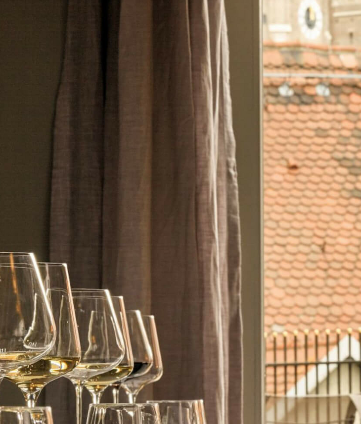 The LOUIS Grillroom l Private Dining at the Viktualienmarkt Set table with a view of the towers of the Frauenkirche through a window in the LOUIS Hotel Munich.