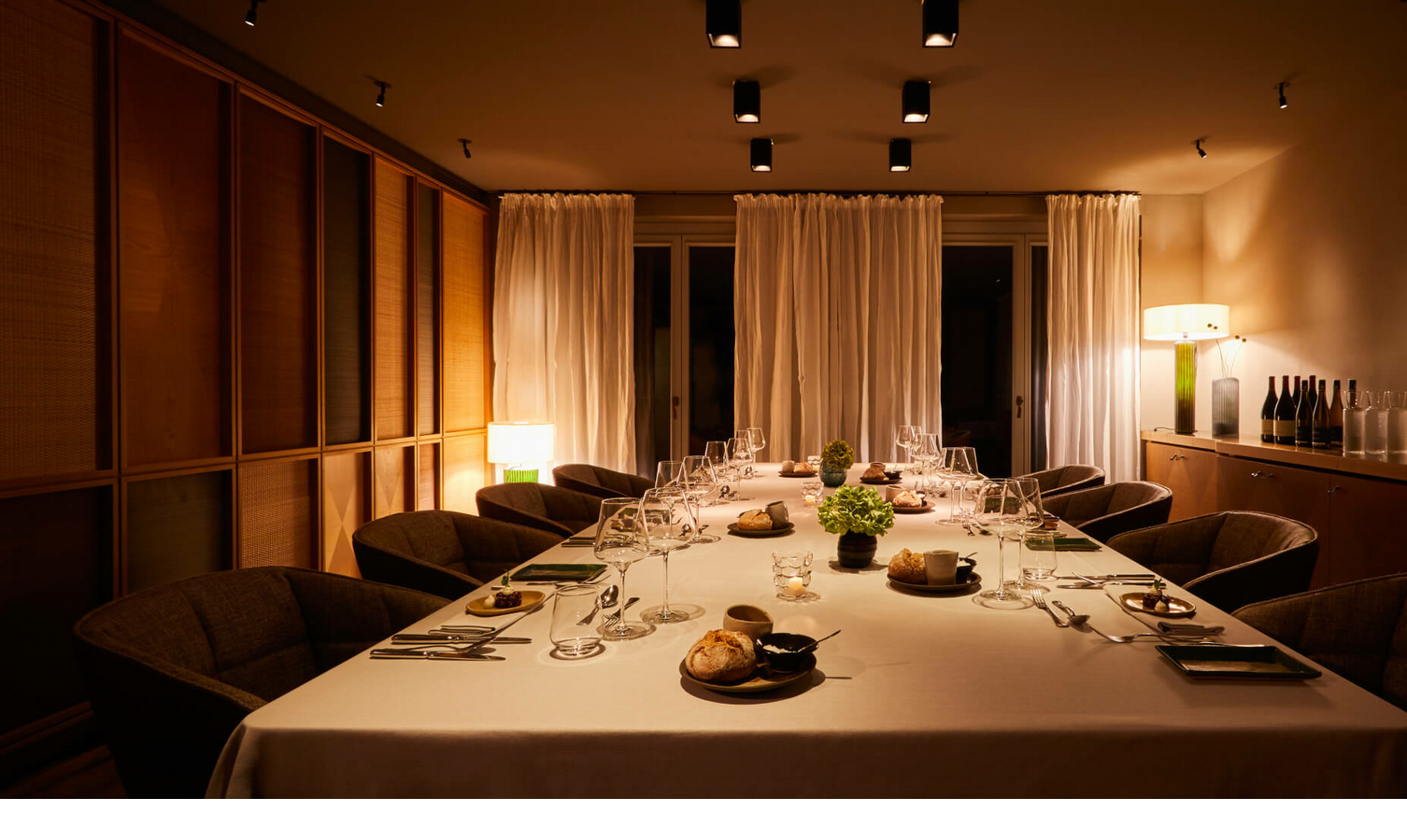 The LOUIS Grillroom l Private Dining am Viktualienmarkt LOUIS Hotel Muenchen Eleganter, gedeckter Esstisch in warm beleuchtetem Raum mit Vorhängen im LOUIS Hotel München.