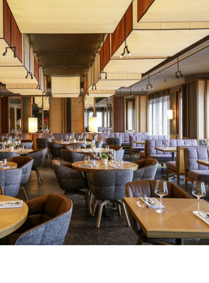 Modernes Restaurant im LOUIS Hotel München mit stilvollen Holztischen, gedeckt mit Gläsern und Besteck, gemütliche Sitzgelegenheiten.