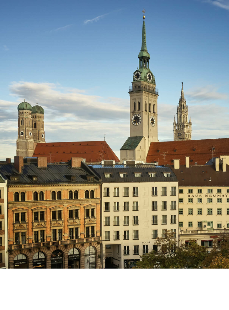 The LOUIS Hotel in Munich | "Fall in love with Munich" deal View of Munich's old town with historic towers and buildings under a clear sky.